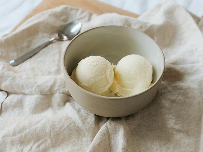 A bowl containing two generous scoops of vanilla ice cream.